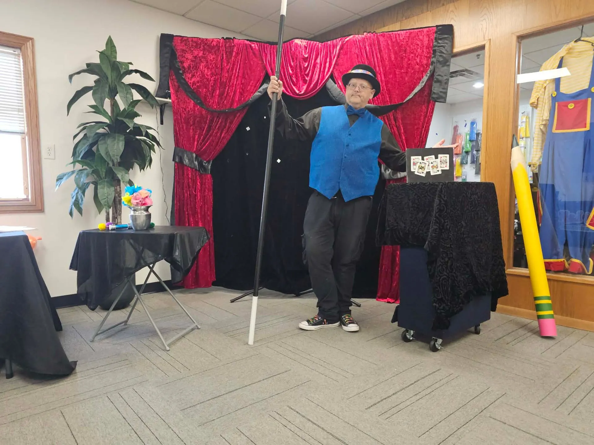 Just 4 Laffs magician performing a magic show on a red-curtain stage