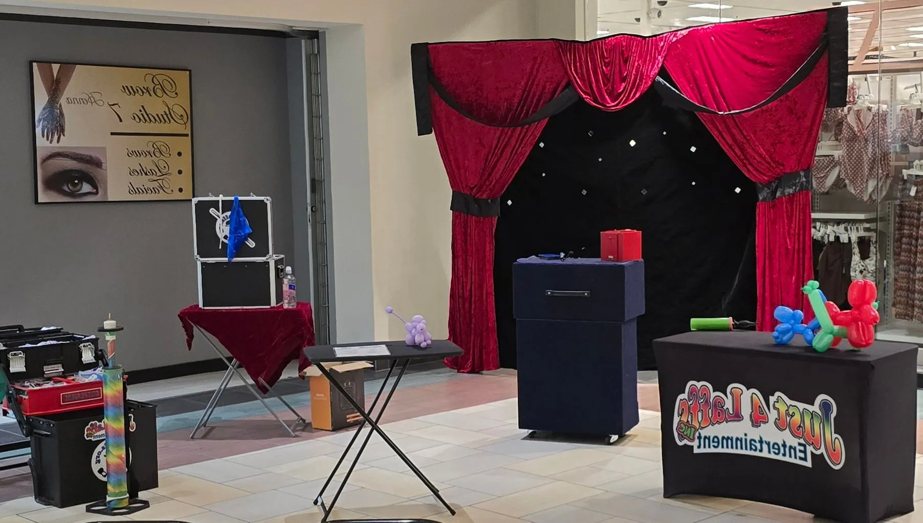 Just 4 Laffs personal event performance setup with red curtains and balloon creations